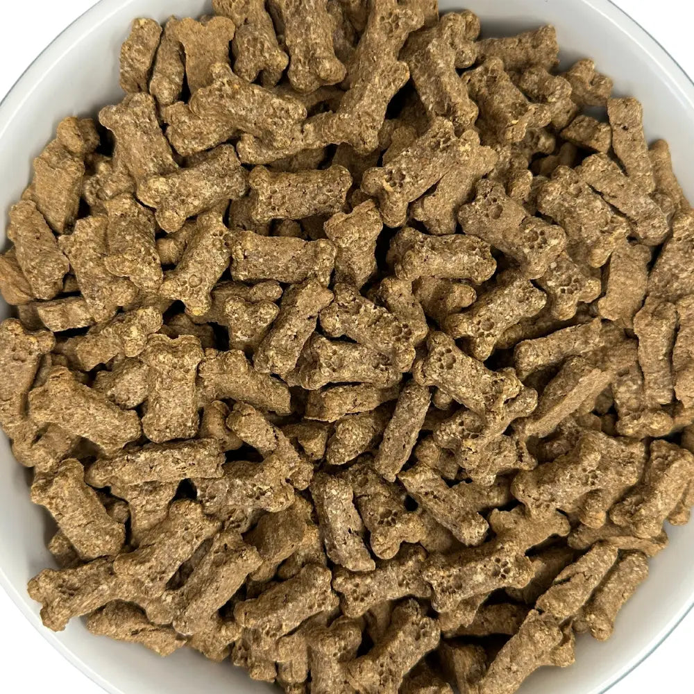 Close-up of bone-shaped Bacon bits dog treats in a white bowl