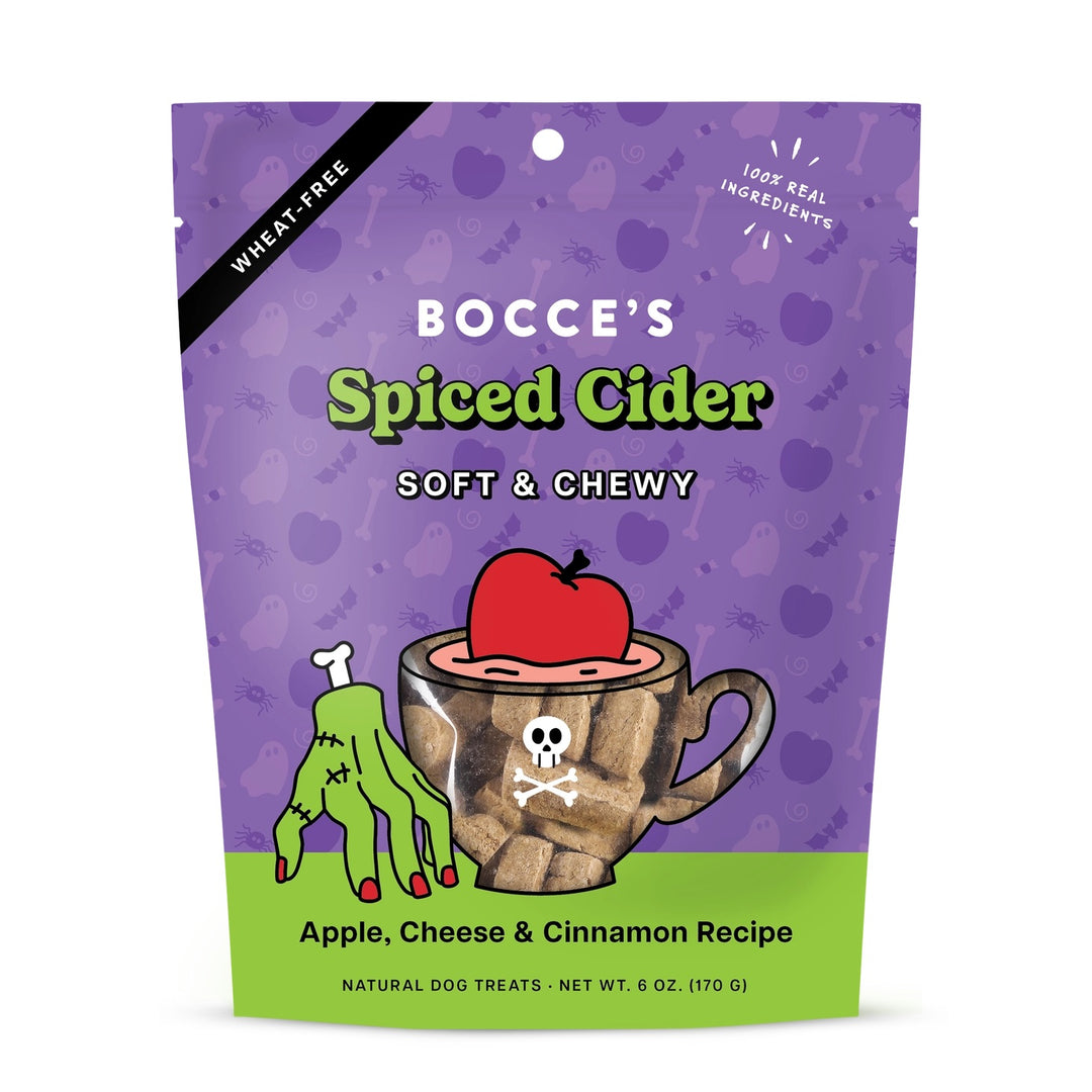 Bocce's Spiced Cider Soft & Chewy dog treats in a 6 oz resealable stand-up pouch. The packaging features a purple Halloween-themed background with ghost and bone patterns, a black diagonal 'Wheat Free' banner, and a green bottom section.