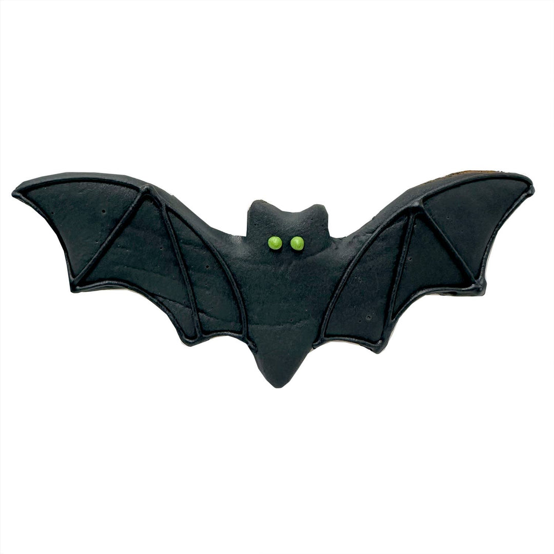 A black bat-shaped item with small bright green eyes, shown against a plain white background.