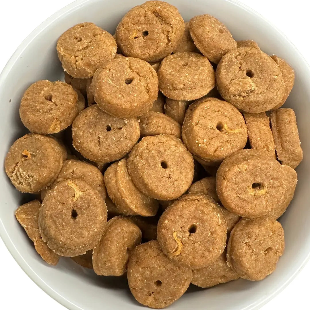 White bowl filled with brown dog treats on a white background