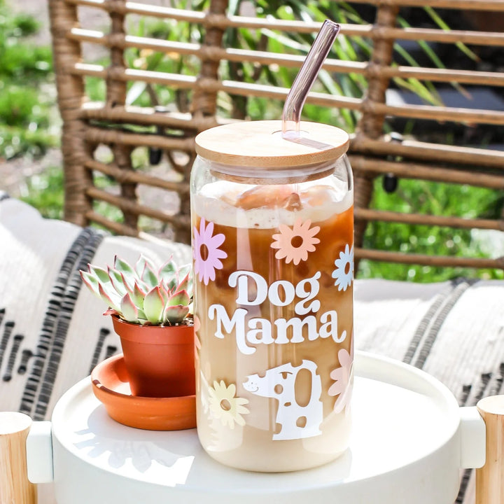 Glass tumbler with 'Dog Mama' text and floral designs on a table outdoors.
