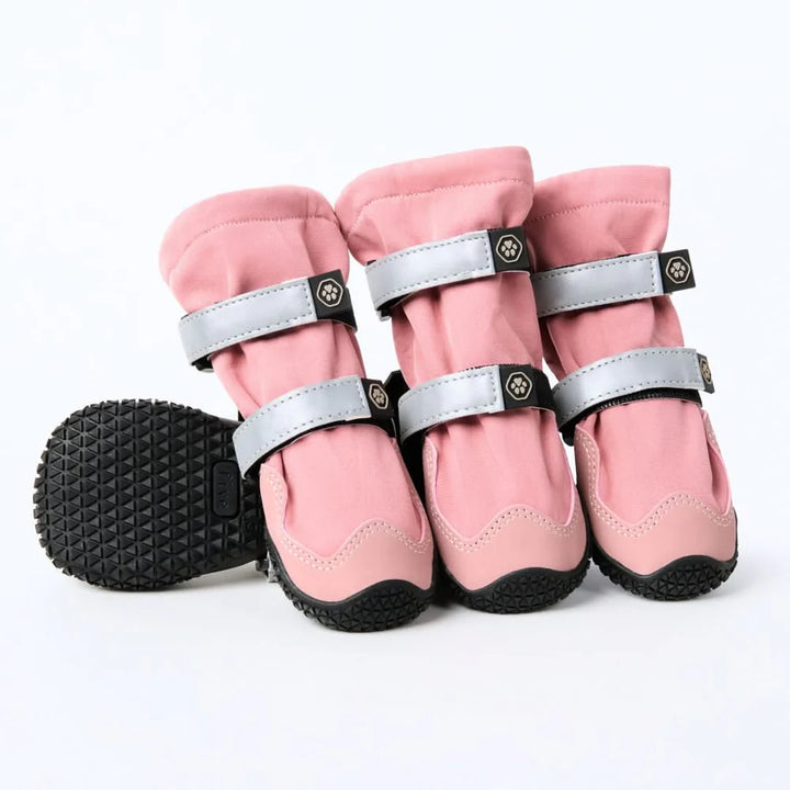 Set of pink flex shell dog boots with black soles on a white background