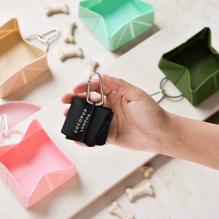 Hand holding a black CocoPup London product with colorful silicone molds in the background.