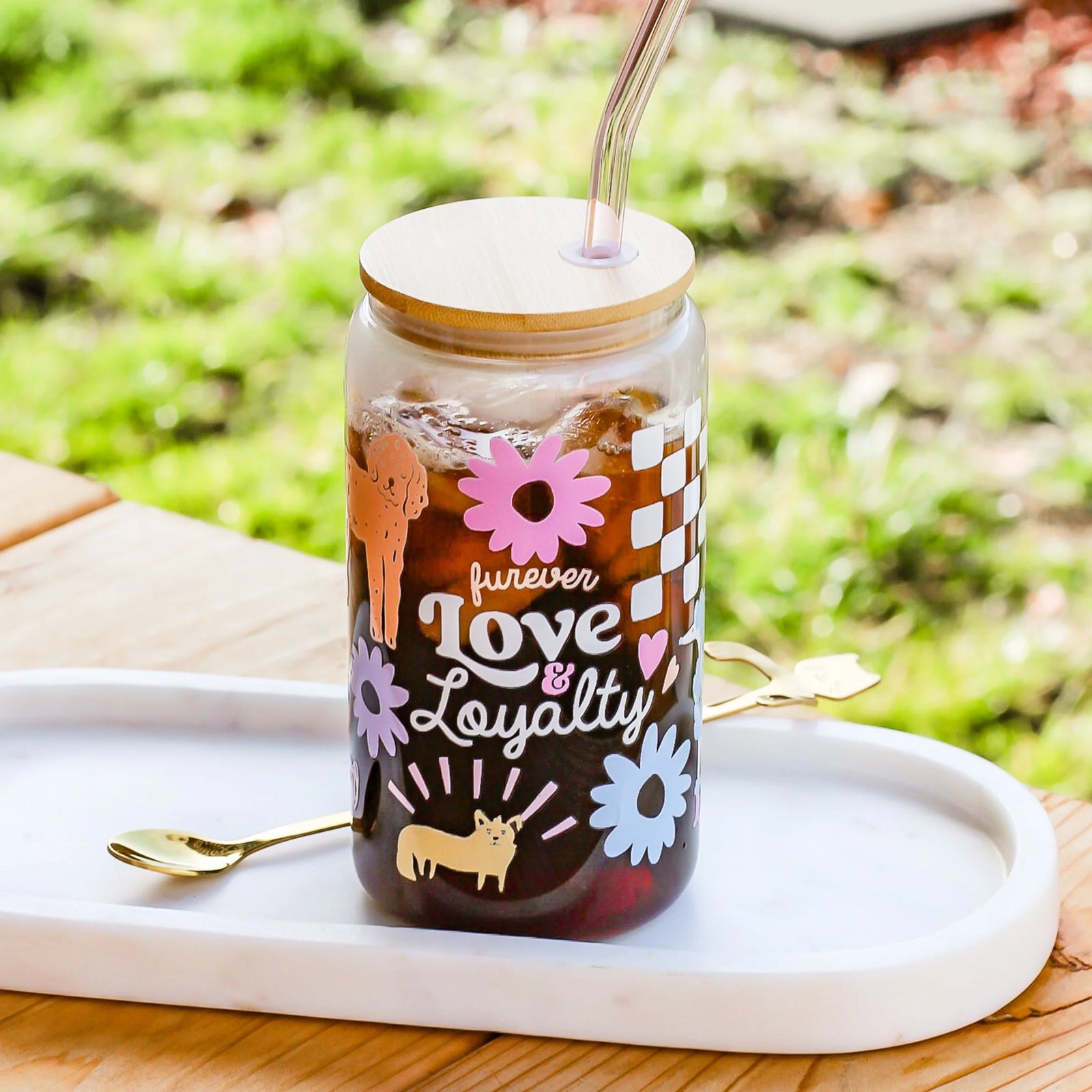 Tumbler with 'forever Love Loyalty' text and illustrations on a white tray outdoors.