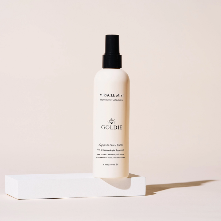 Goldie Miracle Mist bottle on a white platform with a light pink background