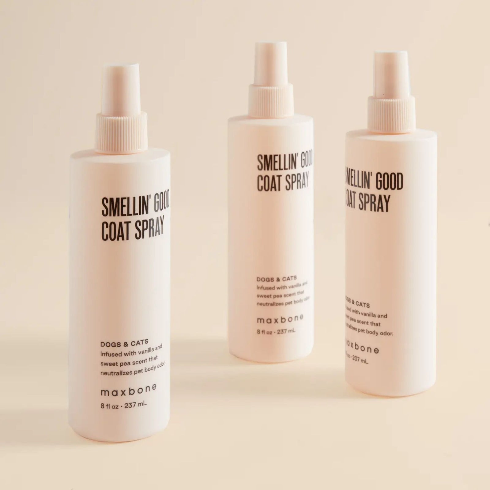 Three bottles of Maxbone Smellin' Good Coat Spray on a beige background