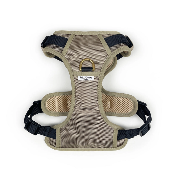 Beige dog harness with black straps on a white background