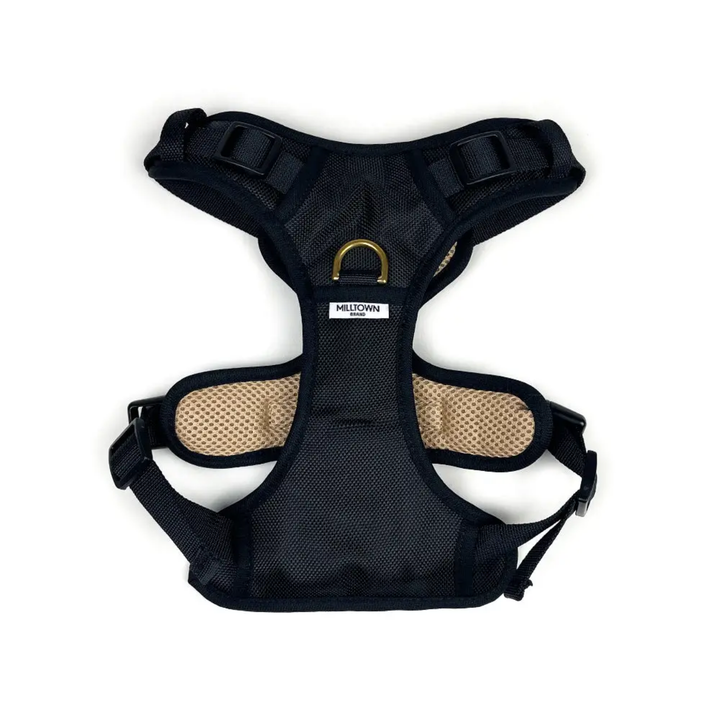 Black dog harness with beige padding on a white background