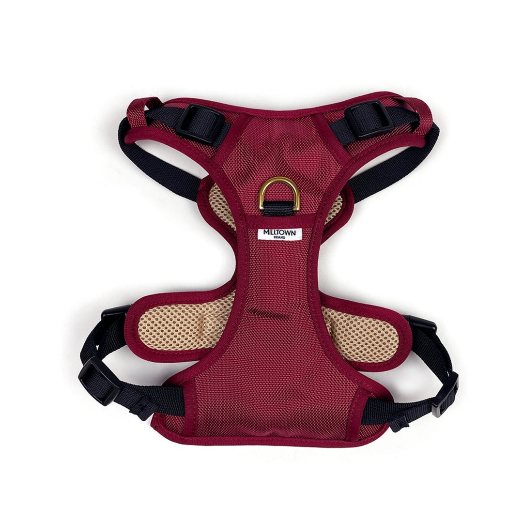 Maroon dog harness with black straps on a white background