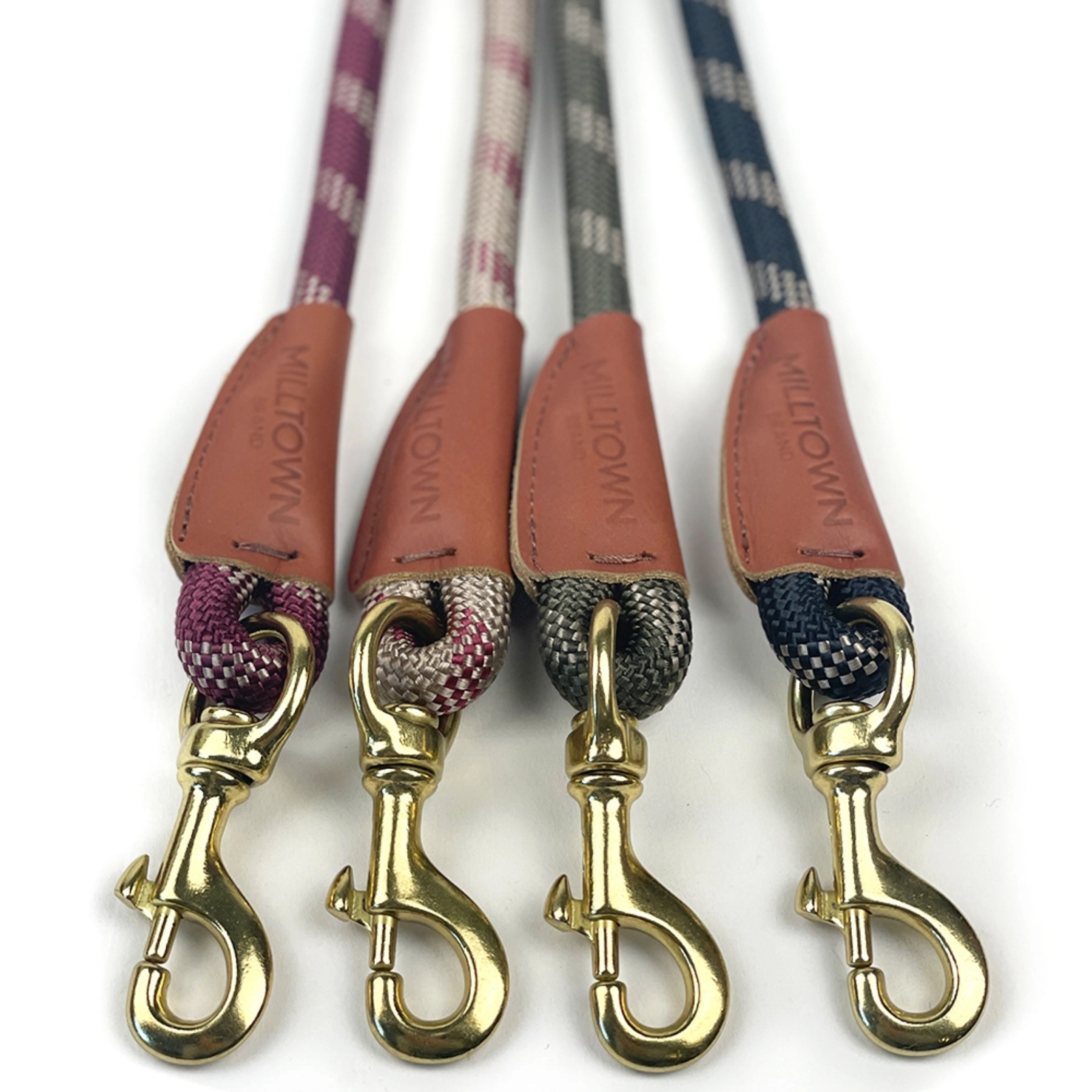 Four dog leashes with patterned handles and gold clasps on a white background