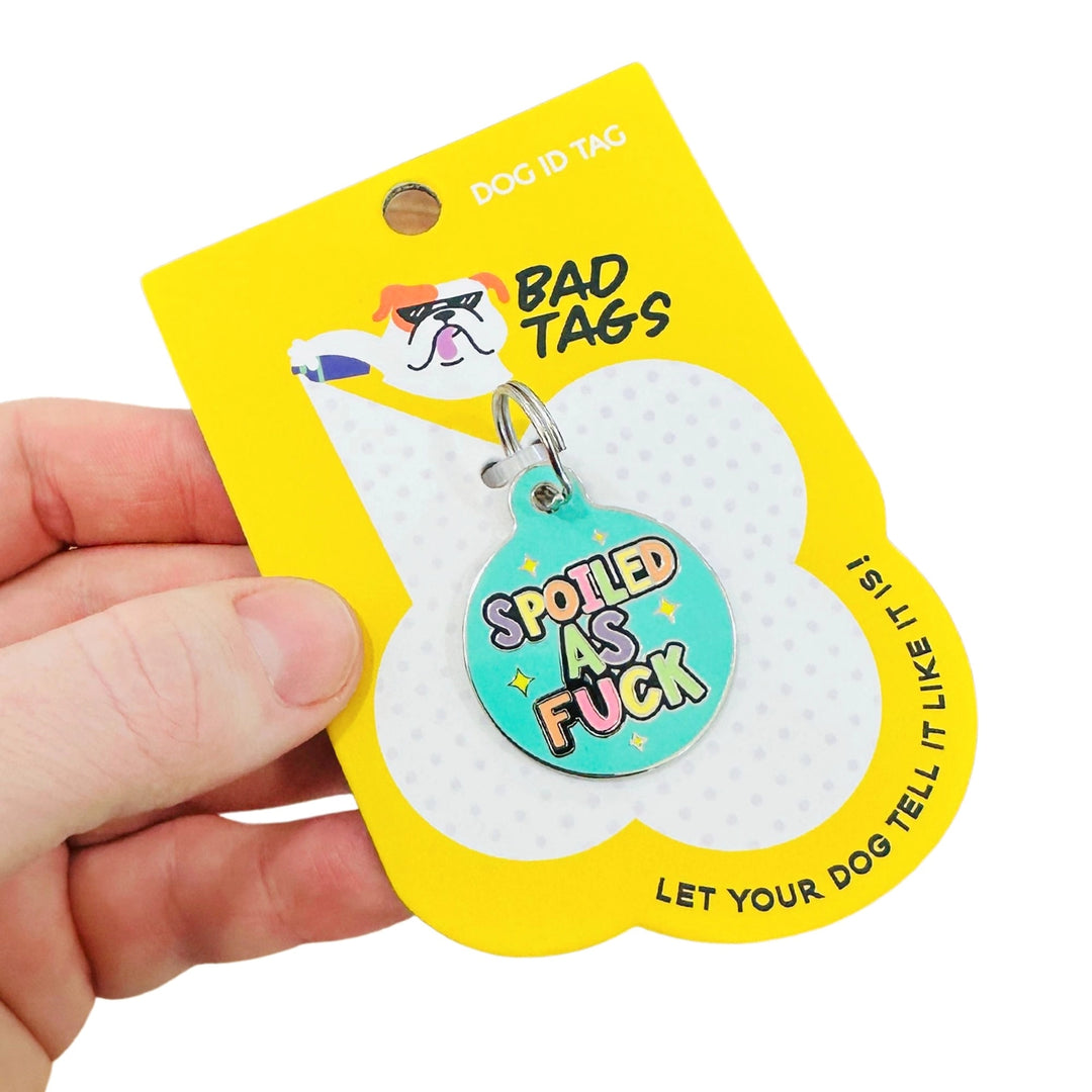 Dog ID tag with colorful text on a yellow 'Bad Tags' packaging