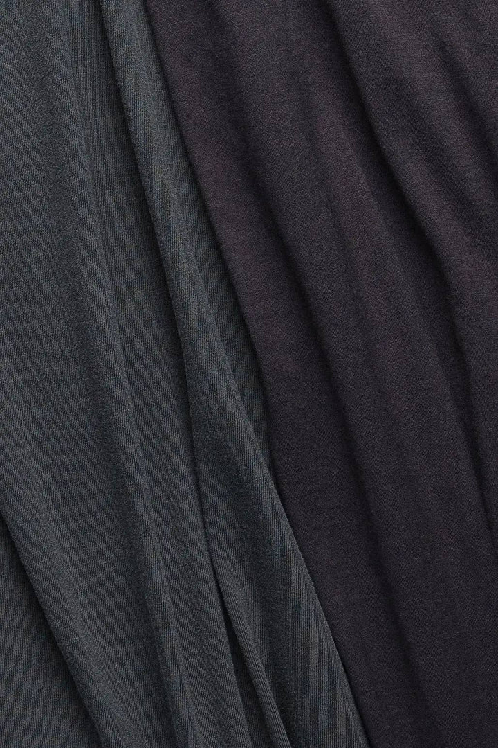 A close-up of draped fabric in two dark charcoal tones, with a subtle sheen and soft folds.